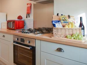 a kitchen with a counter with a stove and a basket of food at Blacksmiths Cottage in Upwey