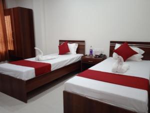 グワーハーティーにあるHOTEL HAREN GRANDのベッドルーム1室(ベッド2台、赤と白のシーツ付)