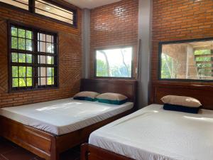 dwa łóżka w pokoju z dwoma oknami w obiekcie Nui Tuong Village Stay w mieście Tân Phú
