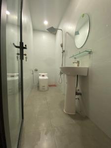 Nui Tuong Village Stay في Tân Phú: حمام مع حوض ومرآة ومرحاض