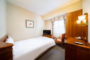 a hotel room with a bed and a desk at KOKO Hotel Nagoya Sakae in Nagoya