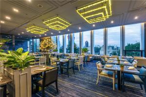 um restaurante com mesas e cadeiras e janelas grandes em Chatrium Residence Sathon Bangkok em Banguecoque