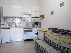 una cocina con armarios blancos y un sofá en una habitación en Maison Port-la-Nouvelle, 2 pièces, 4 personnes - FR-1-229C-78, en Port-la-Nouvelle