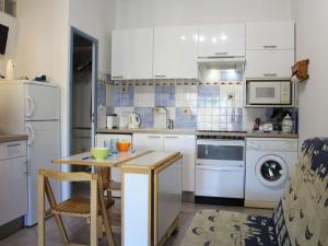 una cocina con electrodomésticos blancos y una mesa con sillas. en Maison Port-la-Nouvelle, 2 pièces, 4 personnes - FR-1-229C-78, en Port-la-Nouvelle