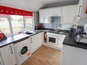 a kitchen with white cabinets and a washer and dryer at Field View in Grimsby