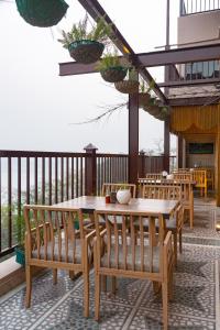 a patio with a wooden table and chairs on a balcony at EllBee Ganga View in Rishīkesh