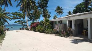 a house with a pathway next to the ocean at SUMMER HOMES BEACH RESORT in Port Barton