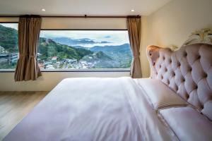 sypialnia z łóżkiem i dużym oknem w obiekcie Windsor's Sunlight Han-Guan w mieście Jiufen