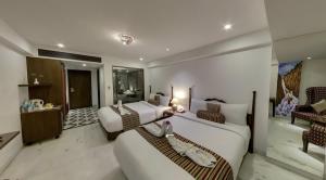 a hotel room with two beds and a living room at EllBee Ganga View in Rishīkesh