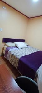 a bedroom with two beds with purple sheets at Bosque Valdiviano Apartment in Valdivia