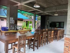 a dining room with a large wooden table and chairs at Green Happy Homestay in Ban Hua Khot