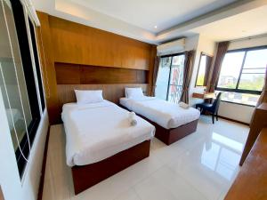 a hotel room with two beds and a desk and window at The D257 Hotel in Phetchabun