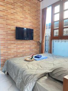 1 dormitorio con pared de ladrillo, cama y TV en Kp. เพลส หลวงแพ่ง (Kp. Place Luang Phaeng), en Ban Bang Bo