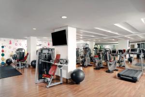 a gym with several tread machines and a flat screen tv at Le Meridien Chiang Rai Resort, Thailand in Chiang Rai