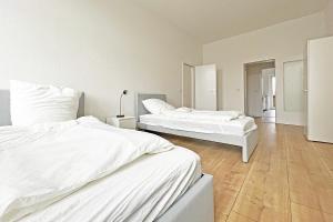 two white beds in a room with wooden floors at Chic Apartment in Jüterbog in Jüterbog