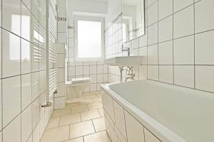 a white bathroom with a tub and a sink at Chic Apartment in Jüterbog in Jüterbog