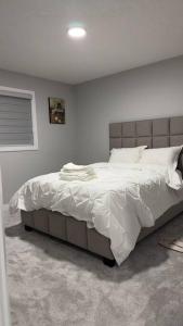 um quarto com uma cama grande e lençóis brancos em 3 Bedroom Single Family Home em Edmonton