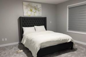 a bedroom with a large bed with a black headboard at 3 Bedroom Single Family Home in Edmonton