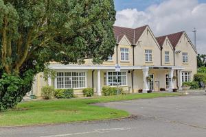 una casa grande con un árbol delante en The Gables Hotel, Birmingham Airport, en Bickenhill