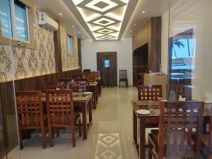 una sala da pranzo con tavoli e sedie in legno di HOTEL IDHAYA a Port Blair