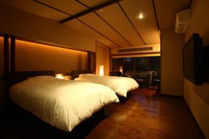 a hotel room with two beds and a television at Sozankyo in Aso