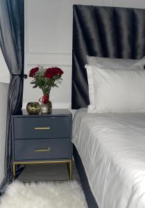 a bed with a night stand with a vase of flowers on it at Little Heaven in Johannesburg