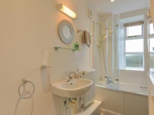 a white bathroom with a sink and a shower at The Old Post Office in Turnchapel