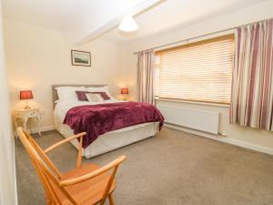 a bedroom with a bed and a chair and a window at Cae Glas in Pwllheli