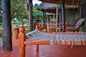 ein Holzbett mit Hängematte auf einer Terrasse in der Unterkunft My Village - Eco Rural Resort in Coimbatore