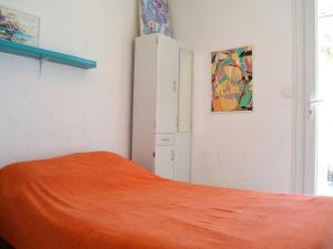 a bedroom with a bed with an orange blanket and a cabinet at Appartement Argelès-sur-Mer, 2 pièces, 5 personnes - FR-1-225-579 in Argelès-sur-Mer