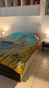 a bed with a colorful comforter in a room at Appartement 90m2 op 70m van het strand. in Ostend