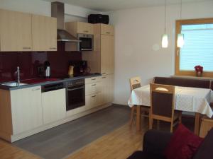 cocina con armarios blancos, mesa y comedor en Apart Lermoos, en Lermoos