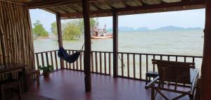 um alpendre com uma rede de descanso e um barco na água em Navareeya House Seaview em Ko Lanta
