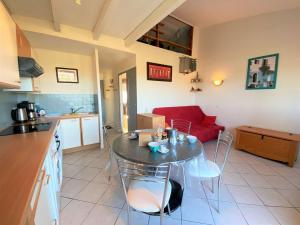 eine Küche und ein Wohnzimmer mit einem Tisch und einem roten Sofa in der Unterkunft Appartement Porticcio, 2 pièces, 4 personnes - FR-1-61-539 in Porticcio