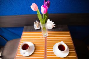 einen Tisch mit einer Vase Blumen und zwei Tassen Kaffee in der Unterkunft Kosmos, mini-hotel in Sankt Petersburg