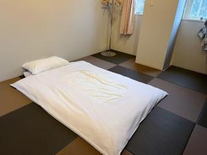 Cama blanca en habitación con suelo de baldosa en Hakuba Sun Valley Hotel Annex, en Hakuba
