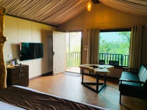 a room with a bed and a television and a table at Niyatma Wayanad Premium Coffee Resort By VOYE HOMES in Wayanad