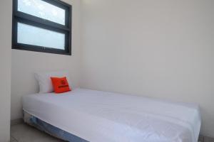 a white bed with an orange pillow in a room at KoolKost near Kampus UNS Solo (Minimum Stay 6 Nights) in Solo