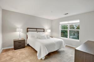 a white bedroom with a bed and a window at Garden Styles Herndon Dulles Airport in Herndon
