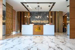 Ein weißer Verkaufstresen in einer Lobby mit Marmorboden in der Unterkunft White Sails Residential Hotel in Batumi
