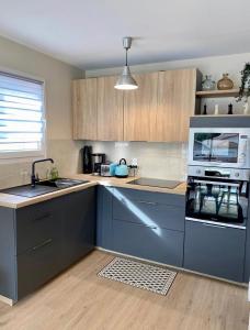 La cuisine est équipée de placards bleus et d'un four avec plaques de cuisson. dans l'établissement Appartement spacieux à Pontaillac, proche plage, à Royan