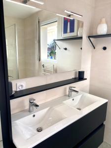 La salle de bains est pourvue d'un lavabo blanc et d'un miroir. dans l'établissement Appartement spacieux à Pontaillac, proche plage, à Royan