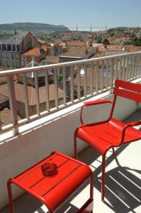 a red chair and stool on a balcony with a view at Mercure Millau in Millau