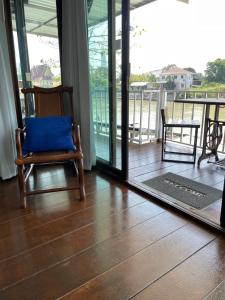 a chair with a blue pillow sitting on a balcony at Baan Keang Chon Ayutthaya บ้านเคียงชล อยุธยา in Phra Nakhon Si Ayutthaya