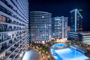 Eine Stadt bei Nacht mit Schwimmbad und hohen Gebäuden in der Unterkunft White Sails Residential Hotel in Batumi + 135 Fotos