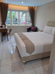 a hotel room with a large bed and a desk at Christine Hotel Jogja in Yogyakarta