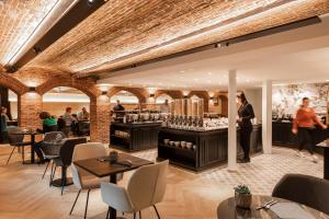 a restaurant with a bar and tables and chairs at Dukes' Academie Brugge - by Dukes' Hotel Collection in Bruges