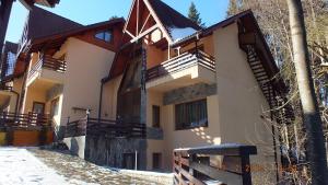 Una casa con nieve en el suelo delante de ella. en Vila Dani, en Sinaia