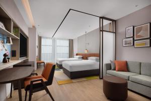 a hotel room with a bed and a couch at Home2 Suites by Hilton Guiyang Airport in Guiyang