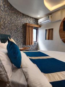 a bedroom with a large bed with blue pillows at Hotel Skyland in Ahmedabad